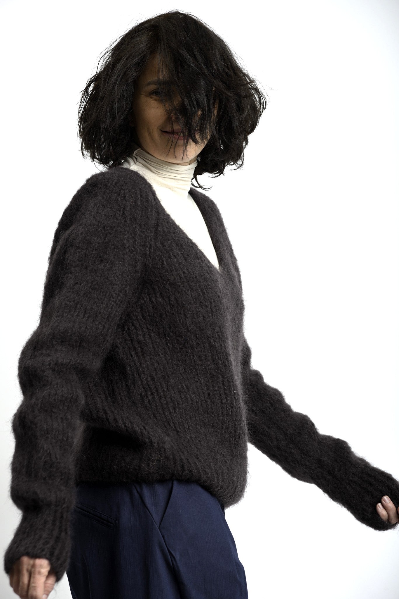 Pulover pufos din mohair, cu decolteu în V și croială lejeră, purtat peste helancă, vedere din față.