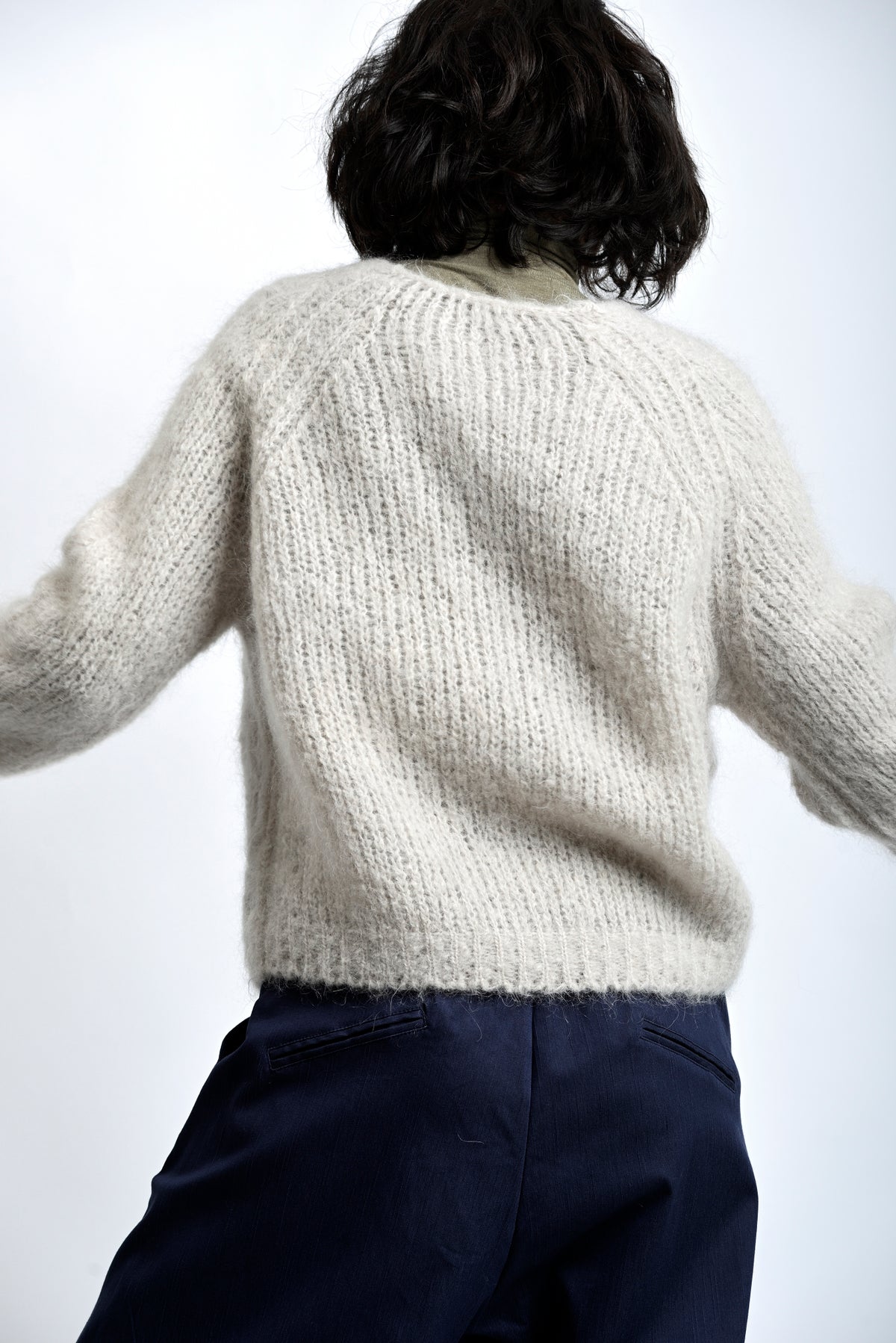 Pulover pufos din mohair, cu decolteu în V și croială lejeră, purtat peste helancă.