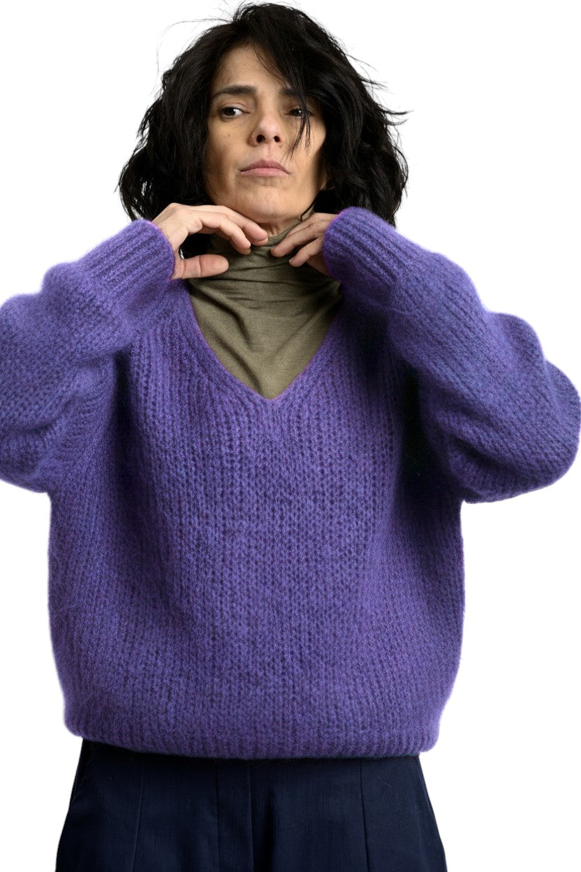 Pulover pufos din mohair, violet, cu decolteu în V și croială lejeră, purtat peste helancă, vedere din față.