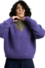 Pulover pufos din mohair, violet, cu decolteu în V și croială lejeră, purtat peste helancă, vedere din față.