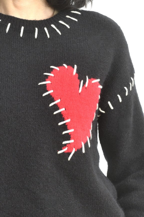 Detaliu de guler la puloverul negru, cu cusături albe contrastante în jurul decolteului.