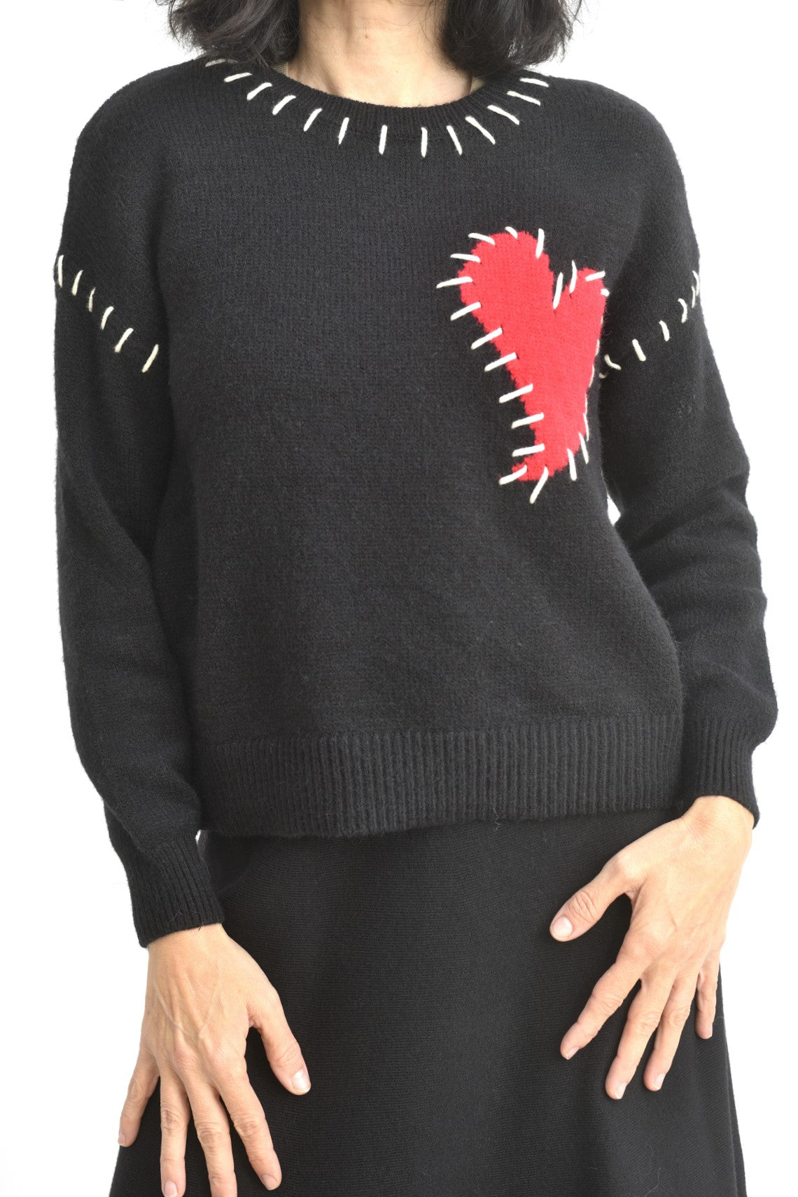 Pulover negru din tricot cu umeri căzuți, decorat cu o inimă roșie mare pe piept și cusături contrastante albe la guler.