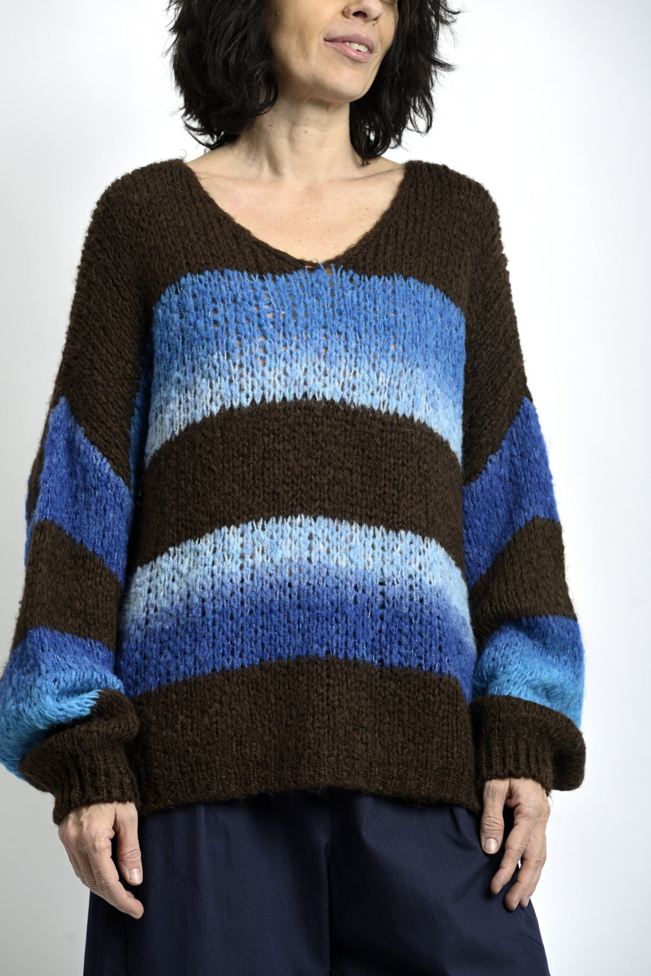Pulover tricotat oversize cu dungi albastre degradé și motiv ancoră, purtat într-o ținută casual de zi.
