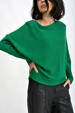 Pulover verde purtat de model, croială lejeră cu umeri căzuți și mâneci lungi, stil casual elegant