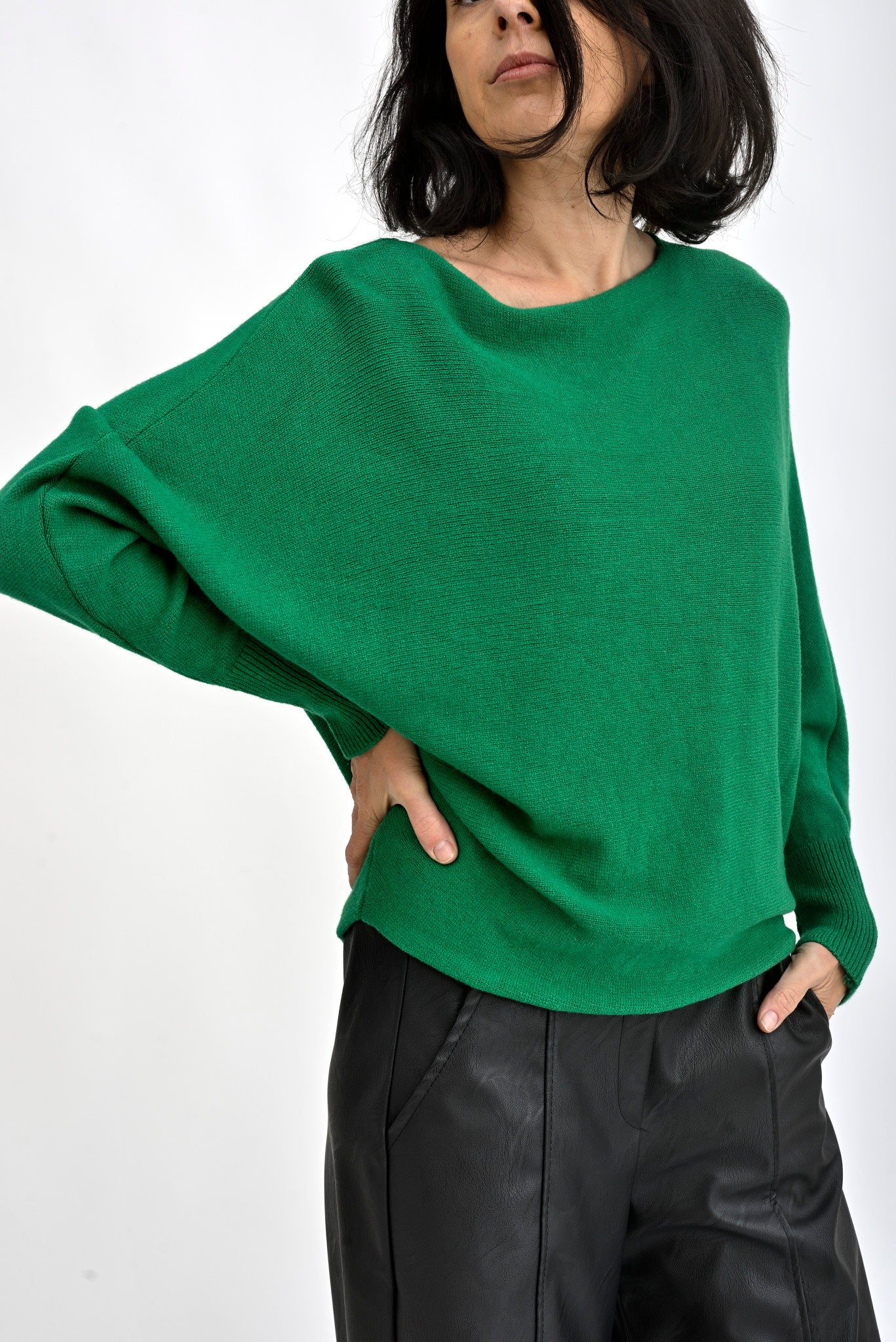 Pulover verde purtat de model, croială lejeră cu umeri căzuți și mâneci lungi, stil casual elegant