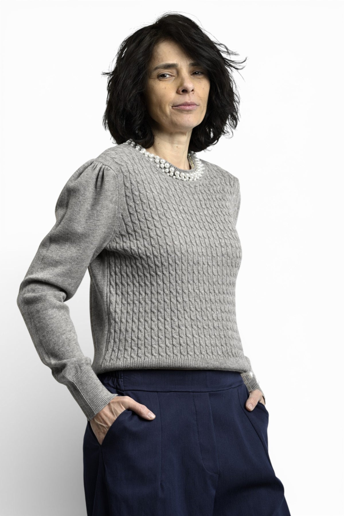 Vedere laterală a puloverului cu torsade și colier decorativ cu perle, evidențiind textura tricotului.