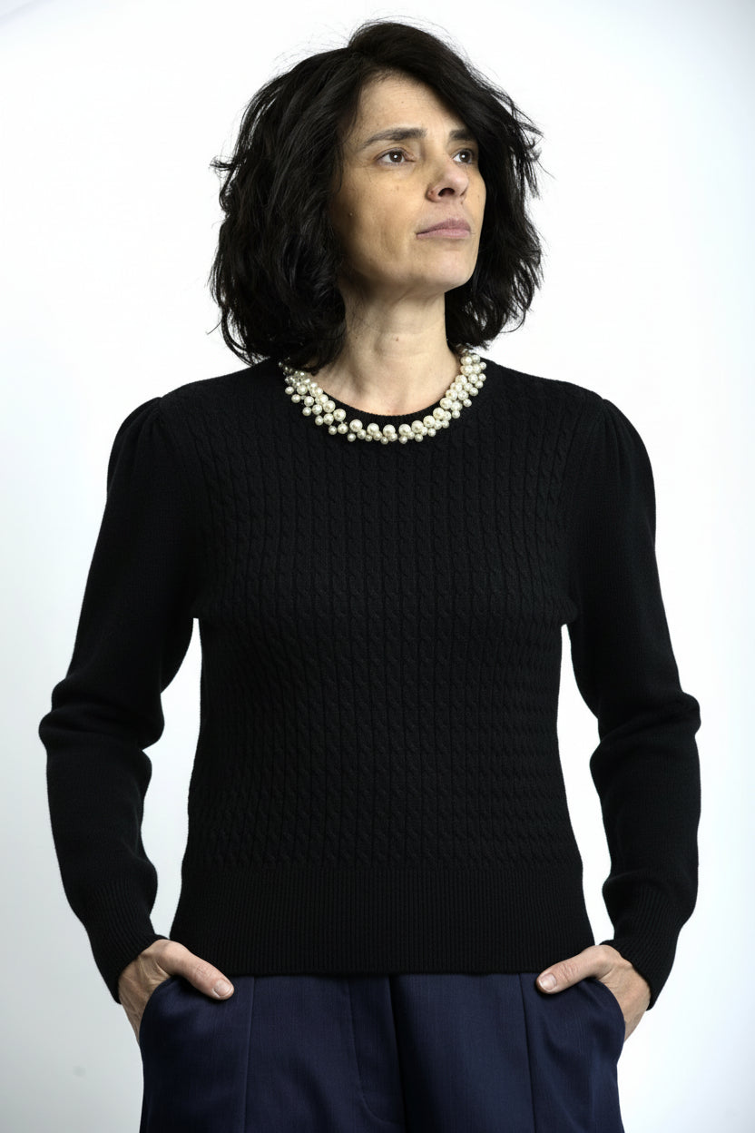 Vedere laterală a puloverului cu torsade și colier decorativ cu perle, evidențiind textura tricotului.