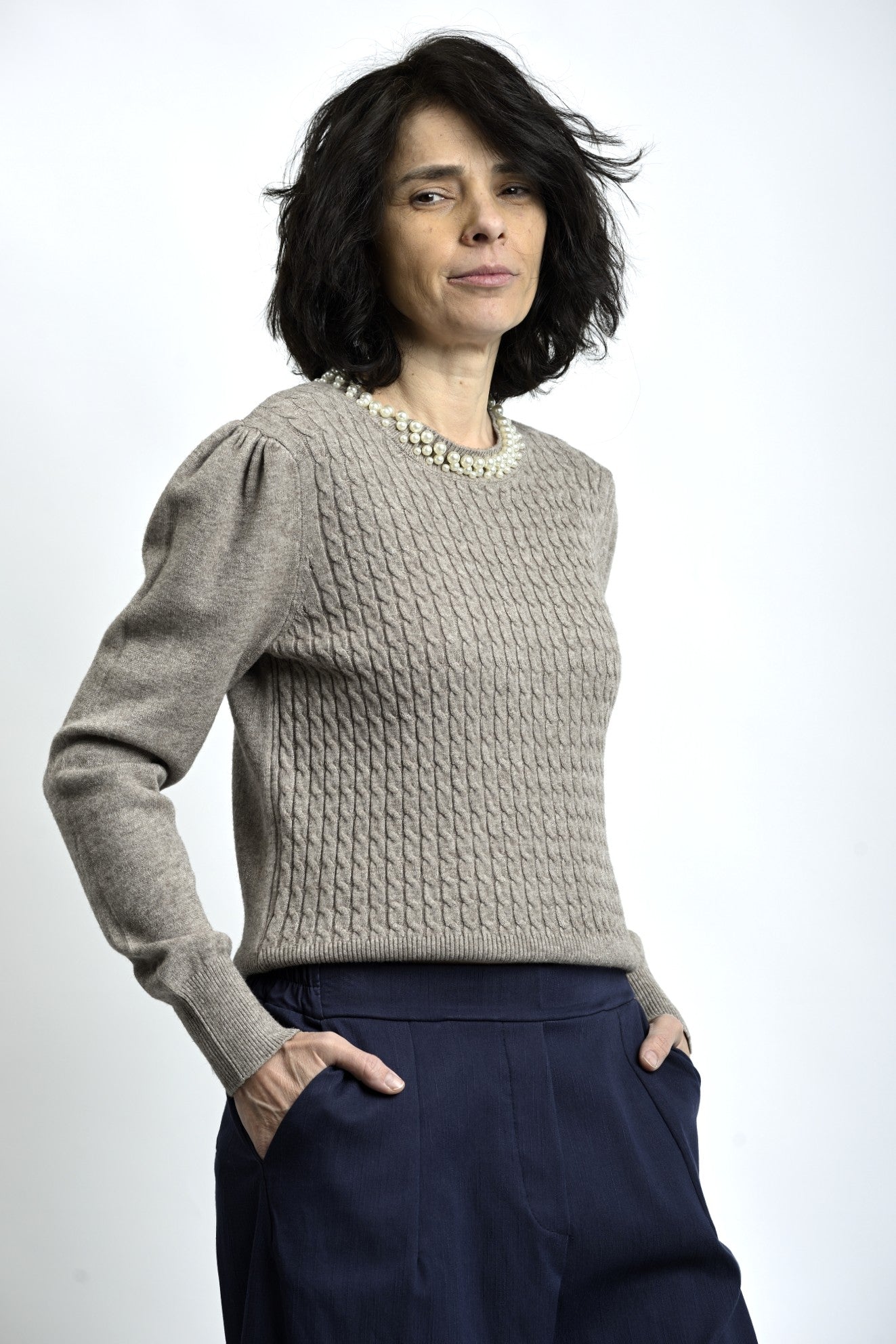 Vedere laterală a puloverului cu torsade și colier decorativ cu perle, evidențiind textura tricotului.