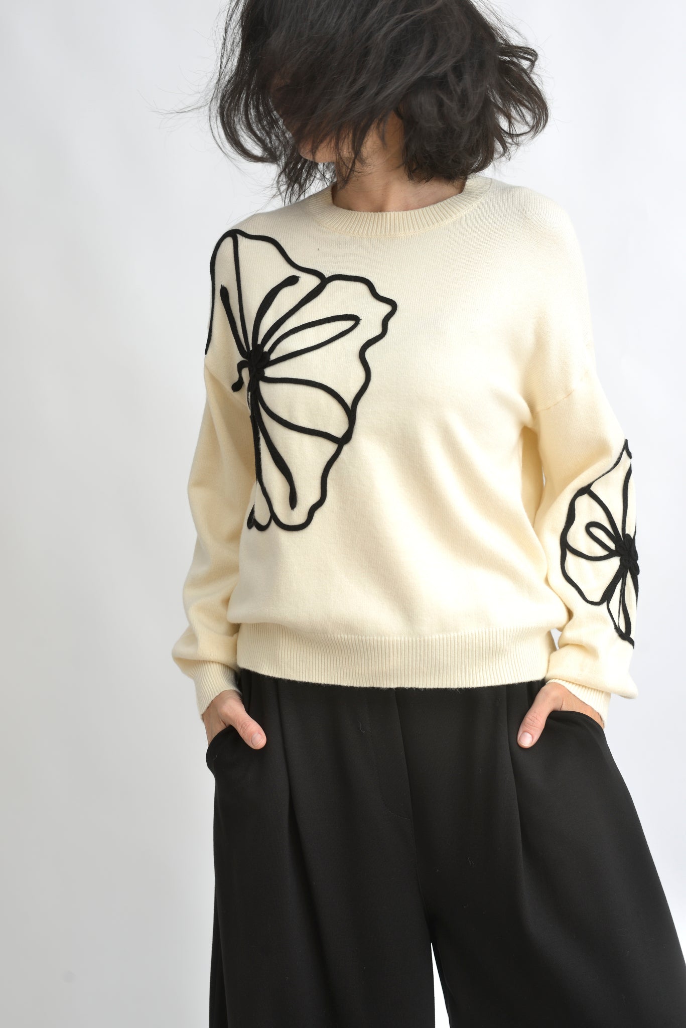 Vedere din spate a puloverului crem din tricot, cu croială lejeră și mâneci lungi.