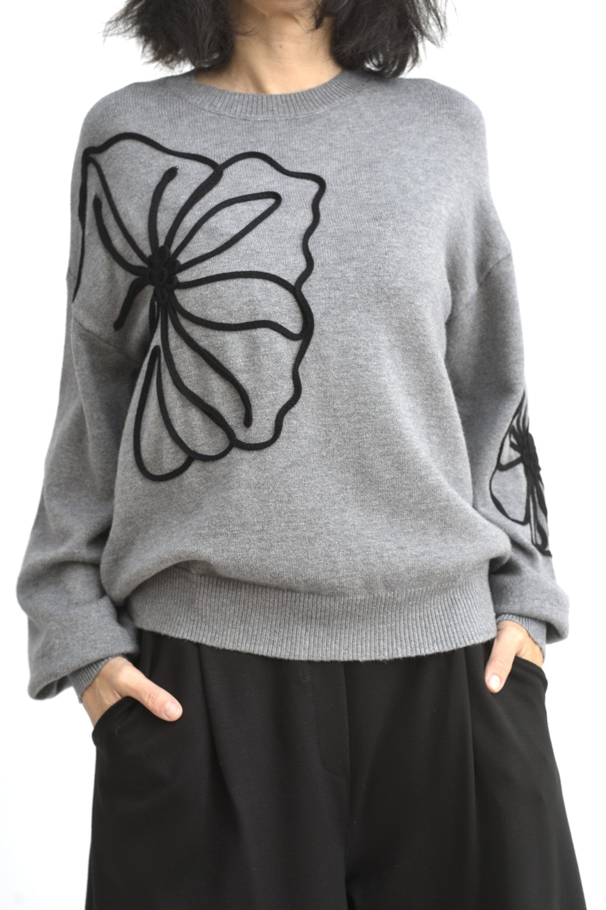 Vedere din spate a puloverului gri din tricot, cu croială lejeră și umeri căzuți.