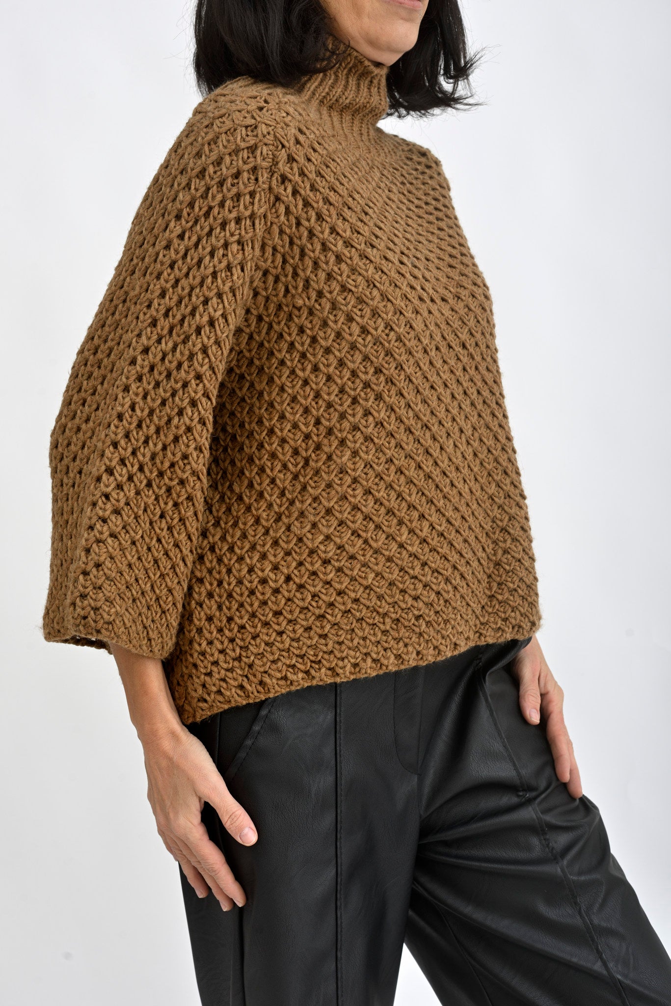 Pulover tricotat damă, văzut din spate, cu umeri căzuți și textură moale.