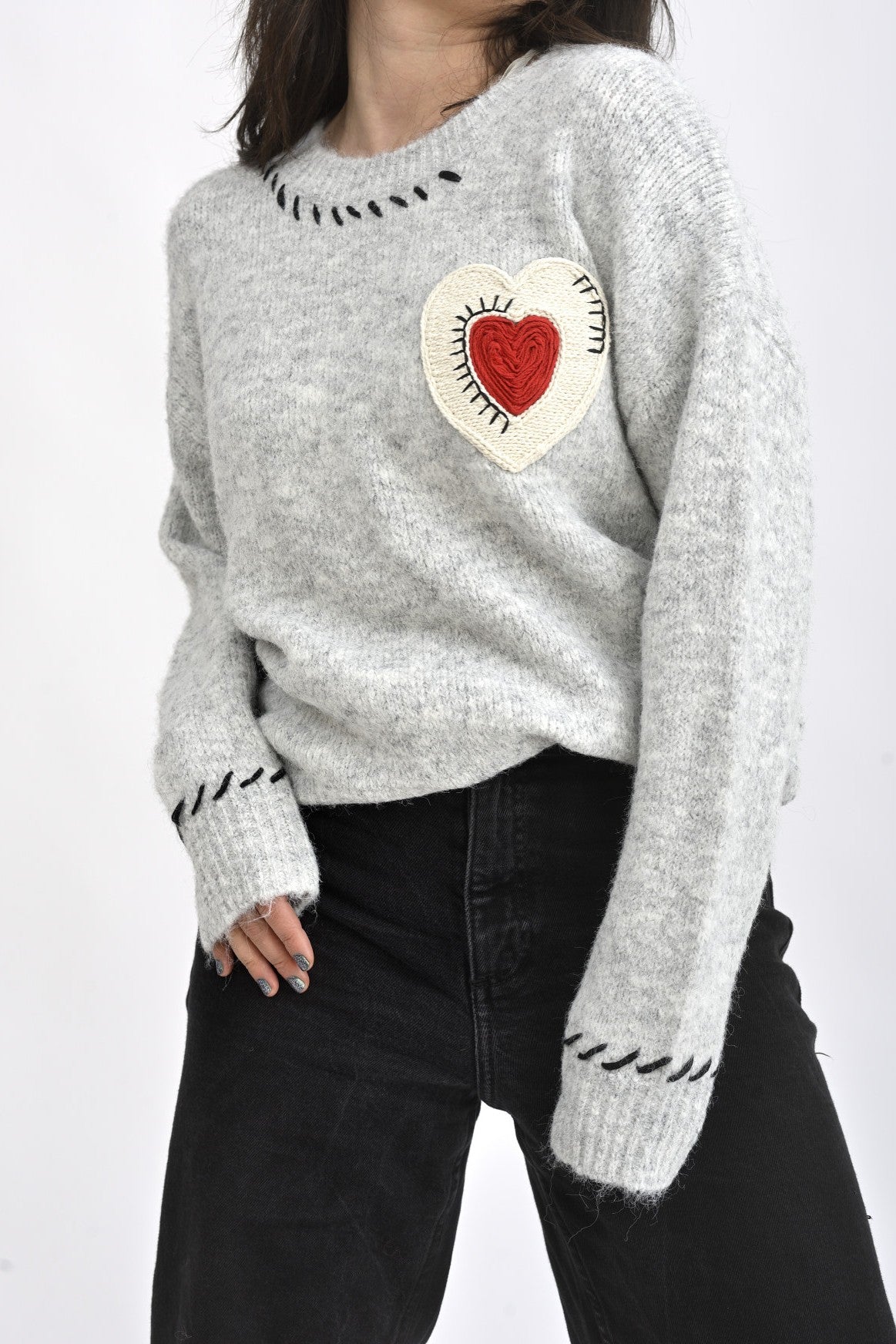 Pulover din tricot gri cu aplicație inimă macramé, fotografie semiprofil ce evidențiază textura materialului.