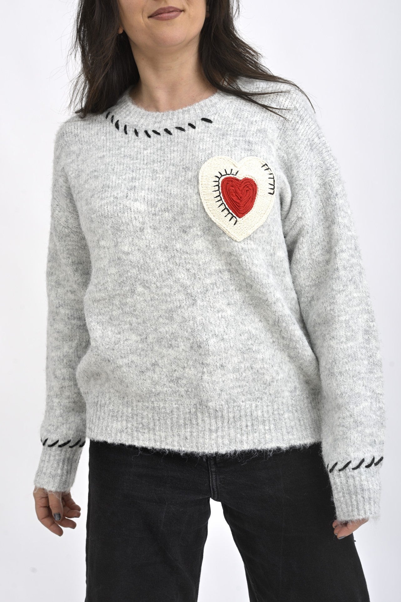 Pulover tricotat gri cu mâneci lungi și inimă macramé decorativă, purtat într-o ținută casual.