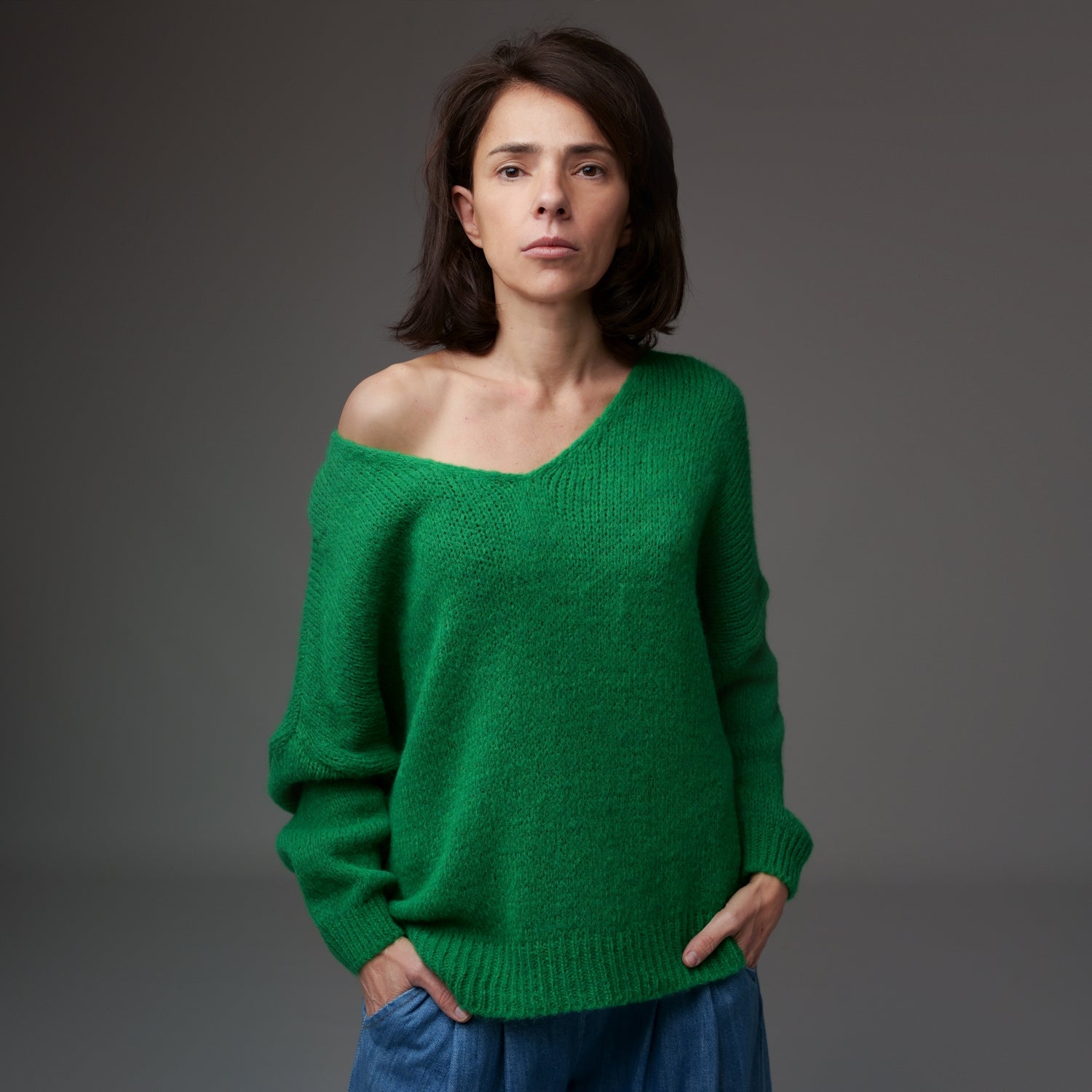 Pulover tricotat verde cu decolteu în V și decupaj lateral, material moale cu fir de lână, model asimetric.