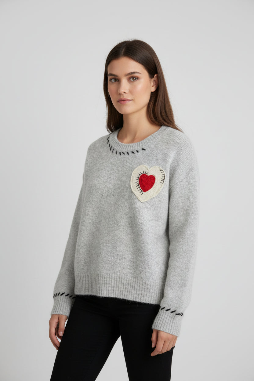 Detaliu aplicație inimă macramé cusută pe pulover din tricot gri, contrast decorativ.