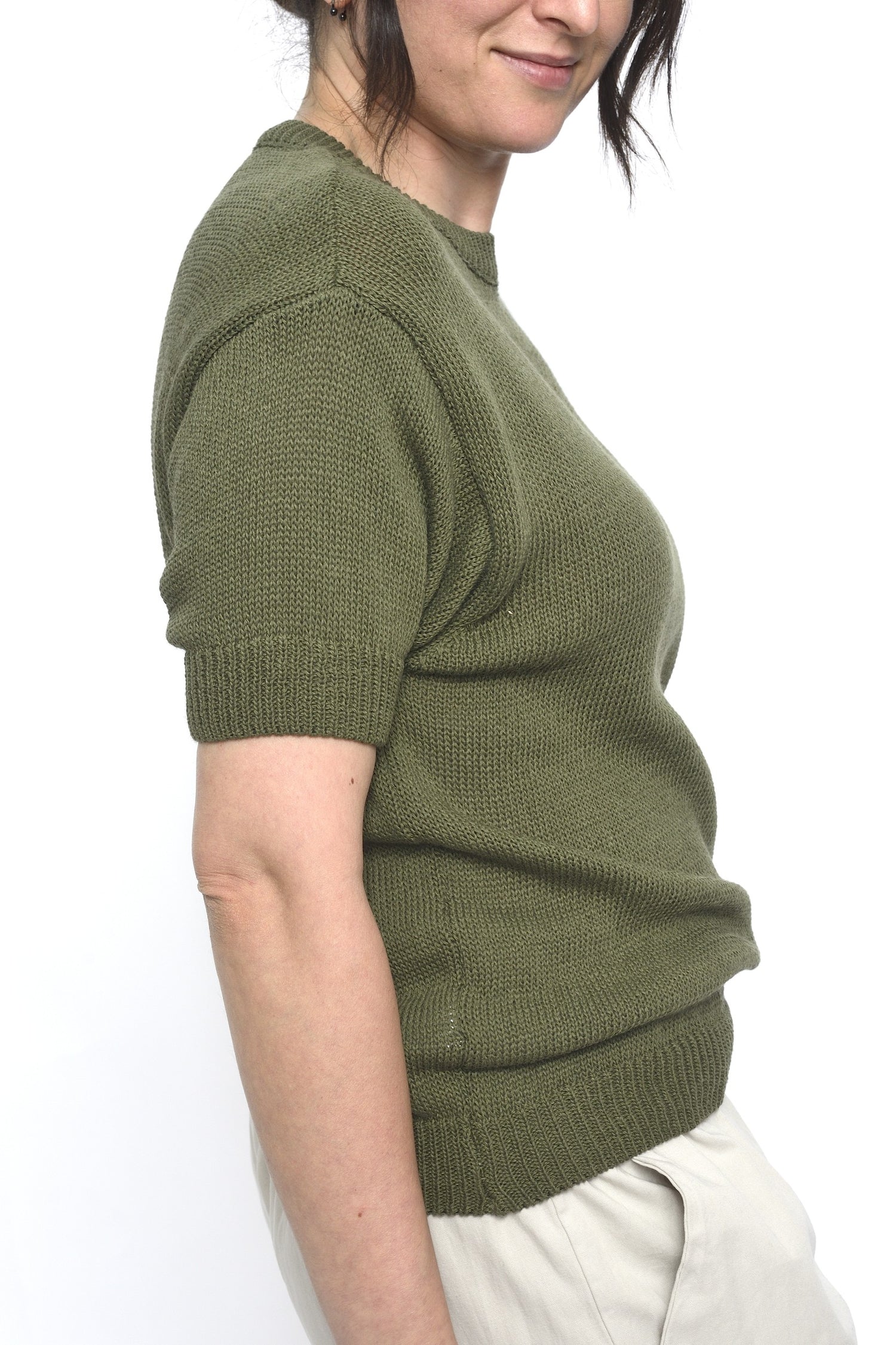 Pulover kaki din tricot, văzut din lateral pe model, cu mânecă scurtă și croială ușor lejeră pentru confort sporit.
