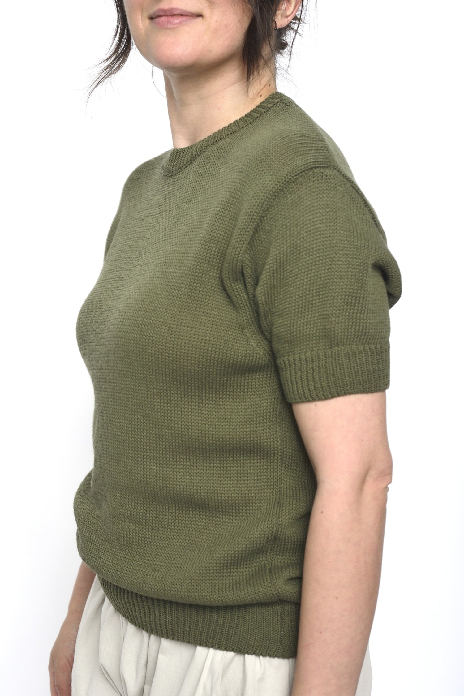 Pulover kaki din tricot, văzut din lateral pe model, cu mânecă scurtă și croială ușor lejeră pentru confort sporit.