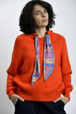 Detaliu tricot pulover portocaliu cu finisaje elastice la manșete și tiv.