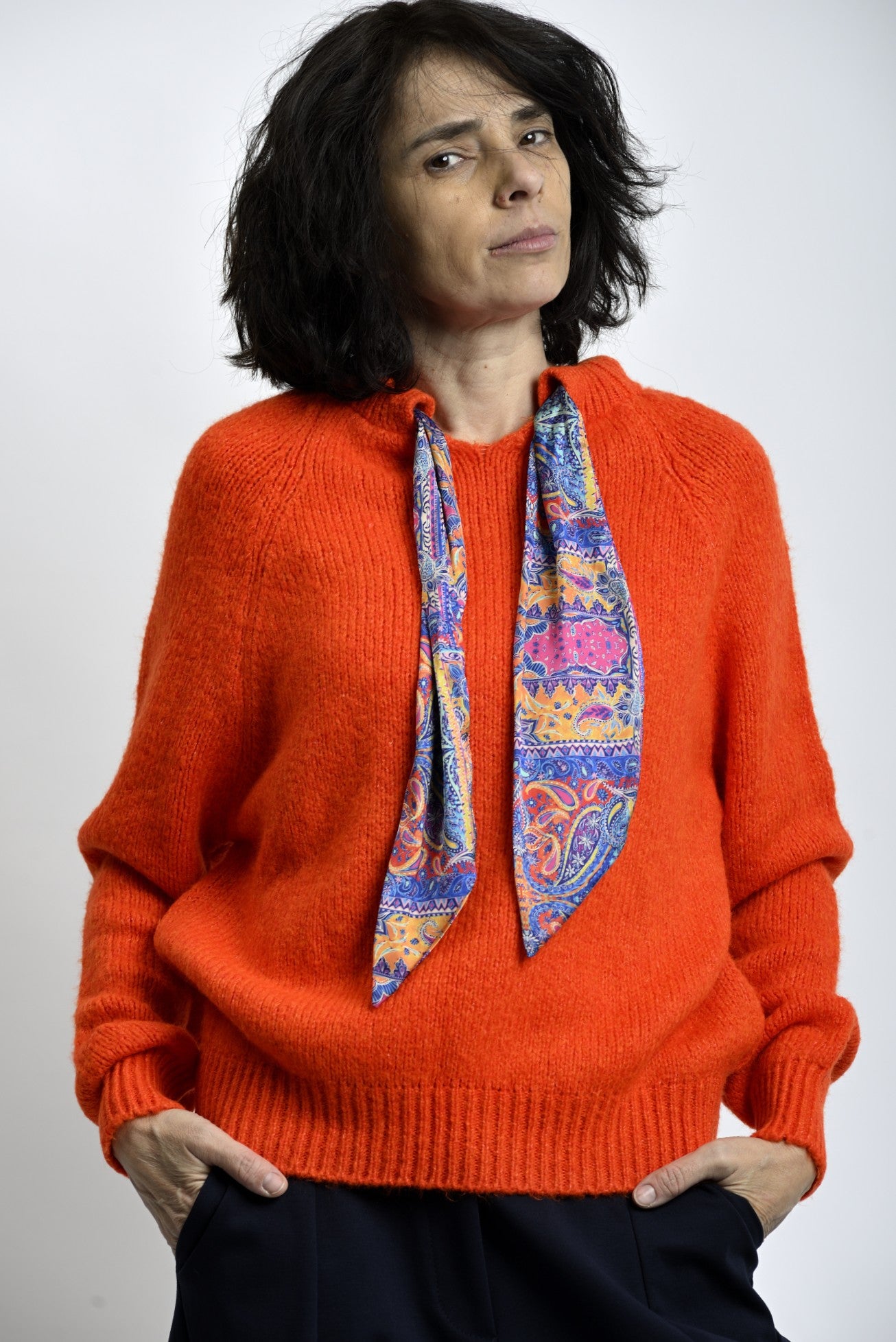 Detaliu tricot pulover portocaliu cu finisaje elastice la manșete și tiv.