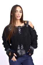 Detaliu decupaje ripped și curele metalice pe puloverul negru.