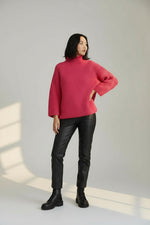 Pulover roz tricotat cu textură solzișori și guler înalt, detaliu frontal al tricotului.