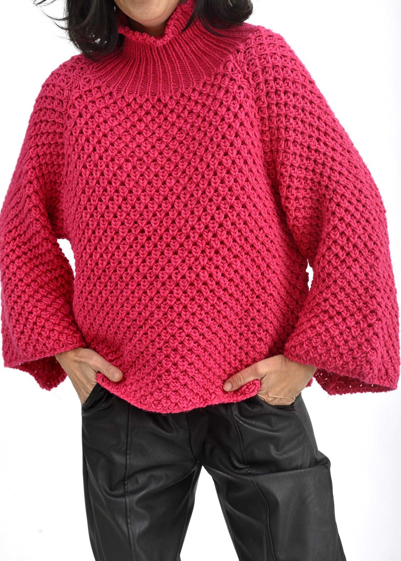 Detaliu mâneci largi și tricot solzișori la pulover roz cu umeri căzuți.