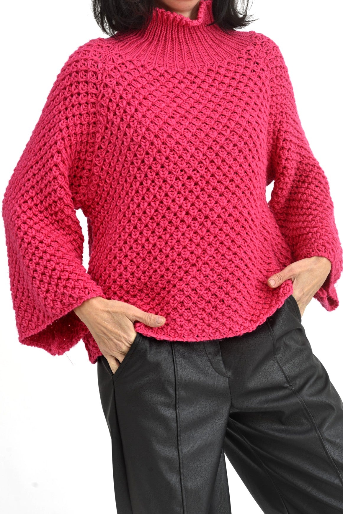 Pulover roz tricotat cu guler înalt, purtat într-o ținută casual cu pantaloni negri.