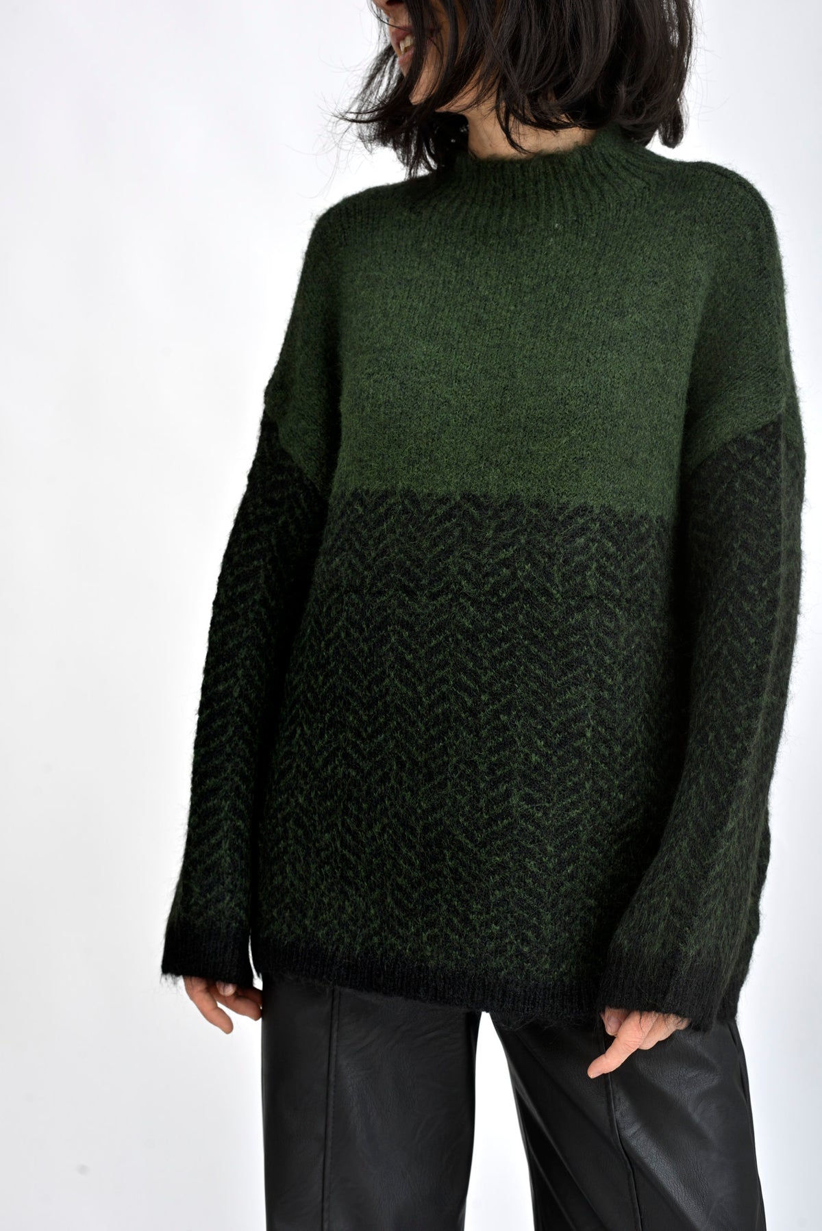 Detaliu textură tricotată în nuanțe de verde, cu model discret și aspect moale.