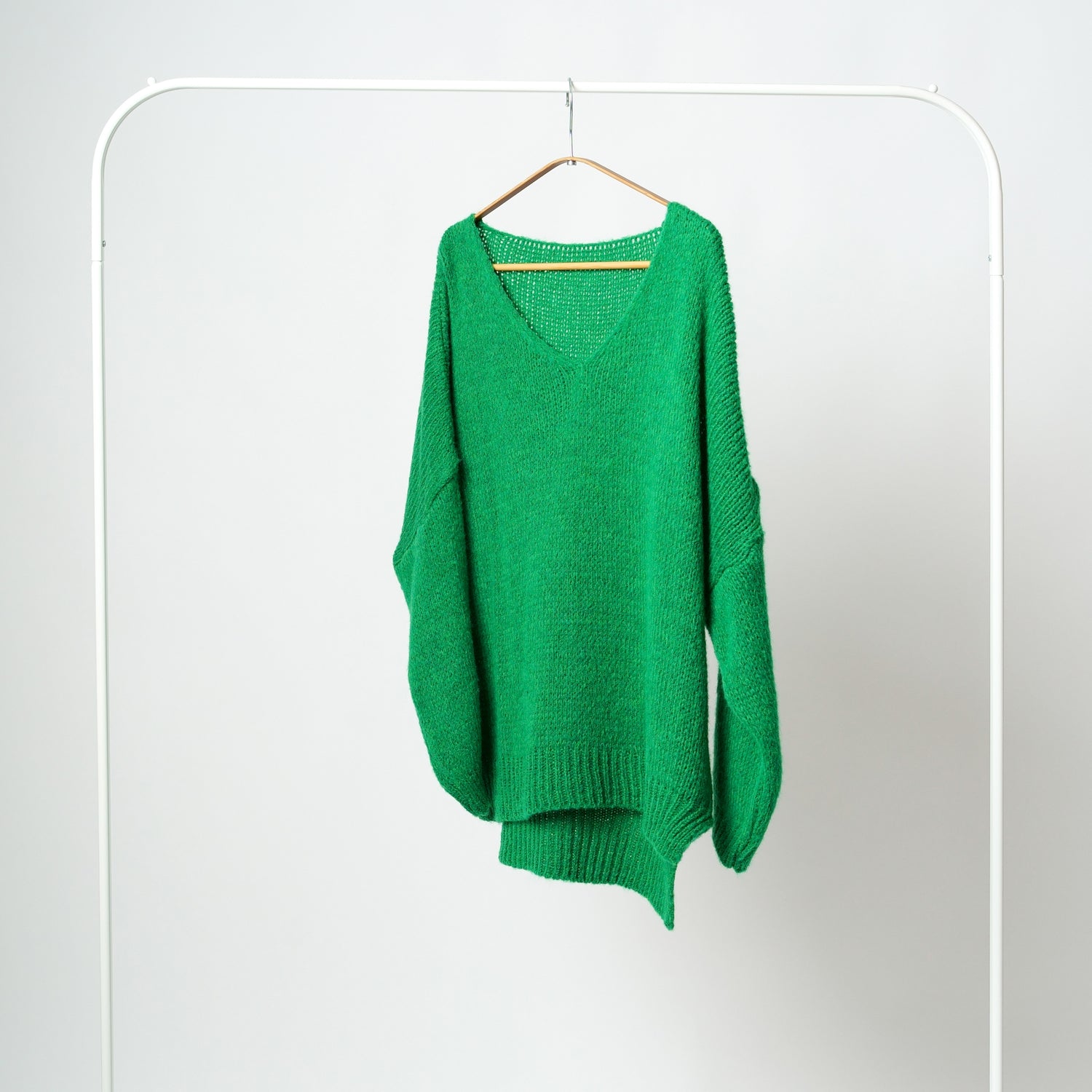 Pulover verde tricotat în V, cu croială asimetrică și decupaj lateral, realizat din material moale.