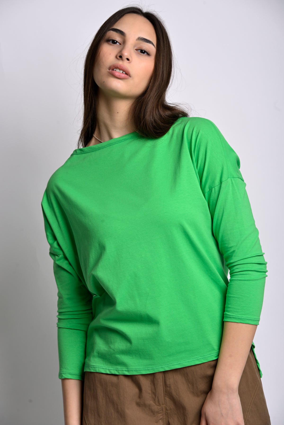 Bluză cu guler bărcuță și croială lejeră, în nuanța verde, purtată de model.