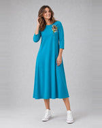 Rochie evazată din jerse cu floare imprimată pe umăr, în nuanța cyan, purtată pe model, All Above Boutique