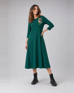 Rochie evazată din jerse cu floare imprimată pe umăr, în nuanța verde închis, purtată pe model, All Above Boutique