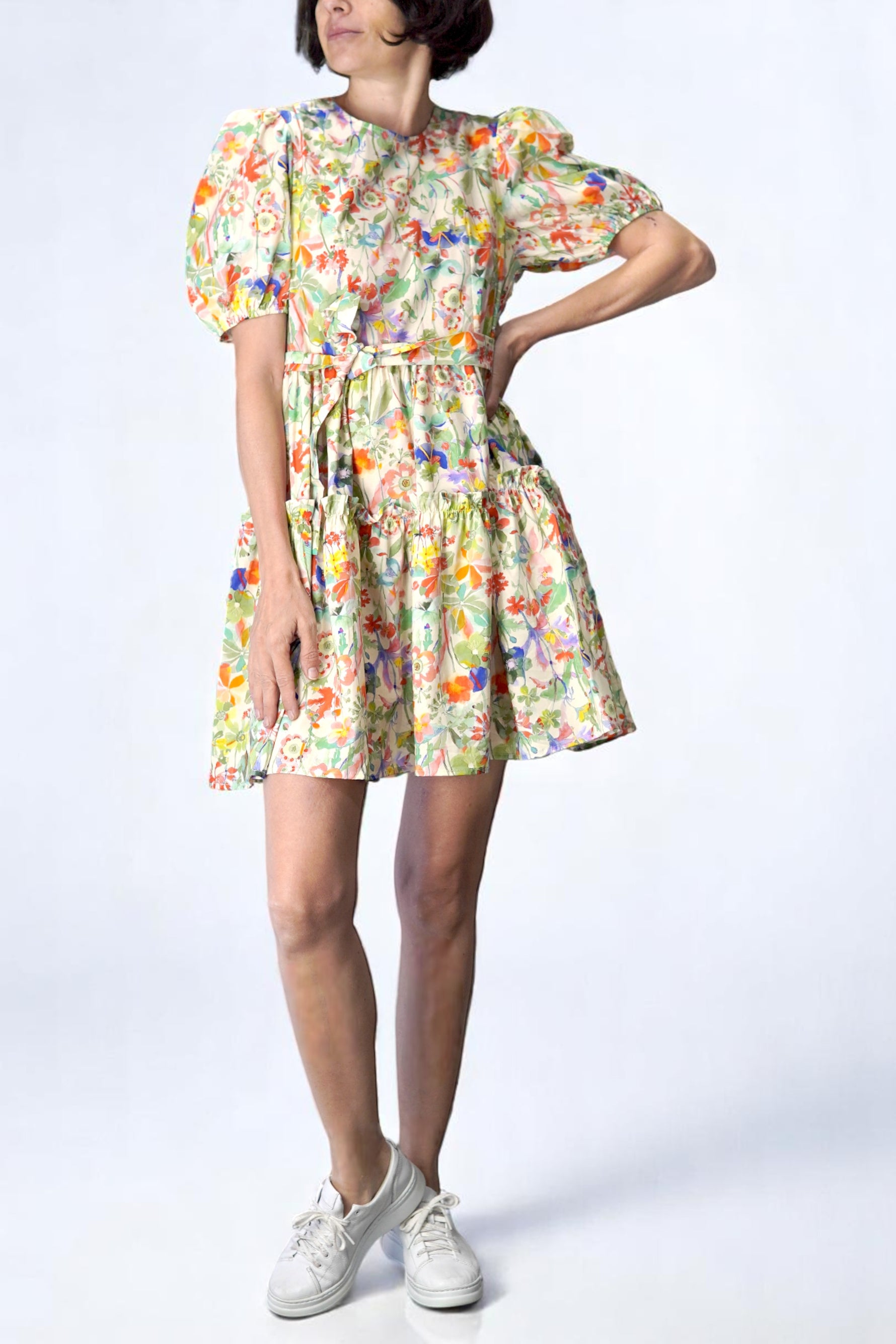 Rochie scurtă babydoll cu imprimeu floral și mâneci bufante, văzută din față, purtată cu pantofi sport albi.
