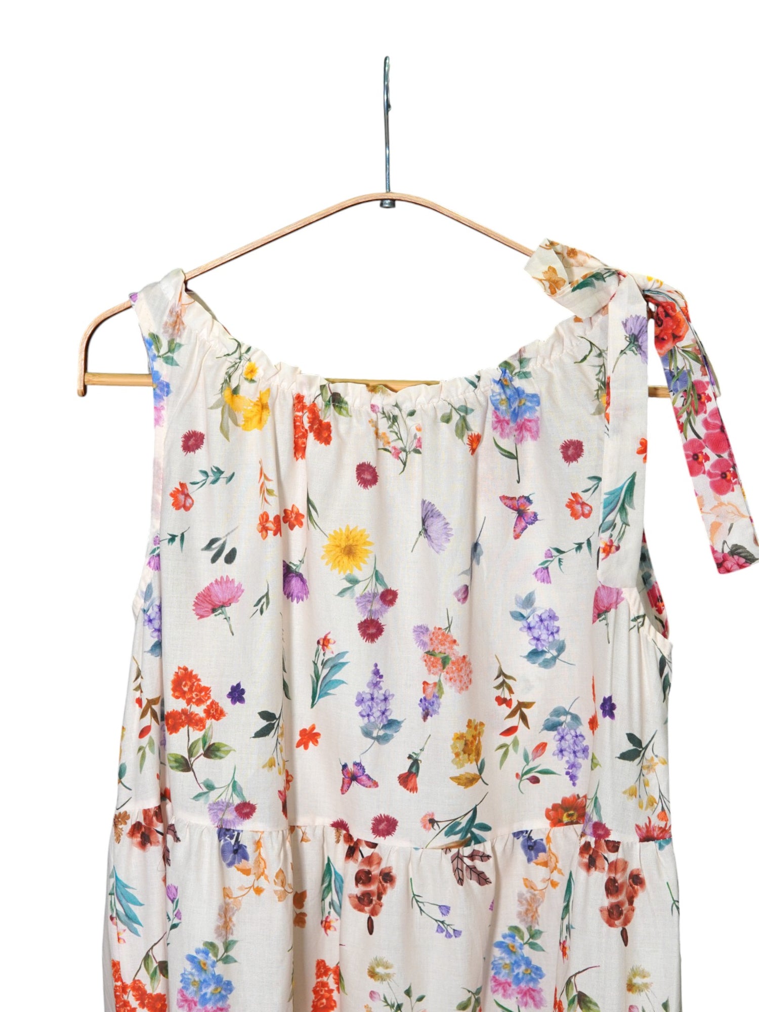 Detaliu fundiță pe umăr și imprimeu floral pe fundal alb al unei rochii babydoll lejere