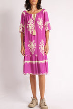 Rochie boho cu decolteu lăsat pe umeri, șnur auriu și imprimeu crem pe fundal fucsia, văzută din față.