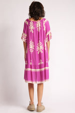 Rochie boho scurtă, cu umerii căzuți, fotografiată din spate, în nuanțe vibrante de roz fucsia și imprimeu crem.