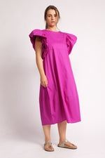Rochie midi fucsia cu croială lejeră și mâneci bufante, purtată cu sandale.