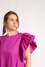  Detaliu rochie fucsia cu mâneci voluminoase și decolteu rotund.