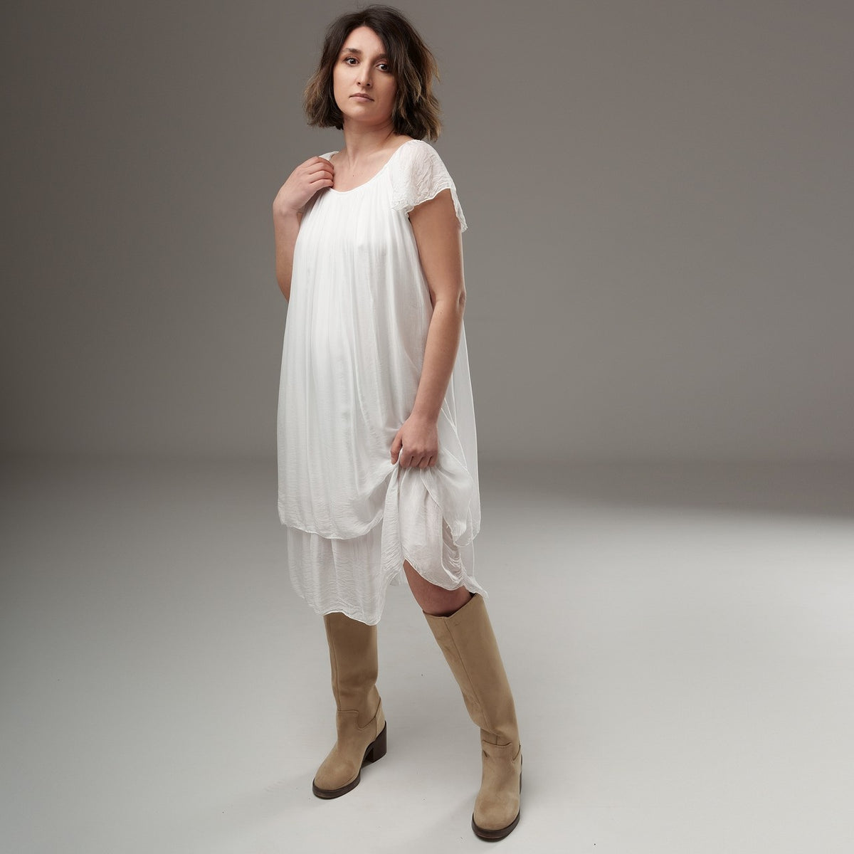 Rochie albă lejeră cu volane la umeri, din material semitransparent, purtată de model