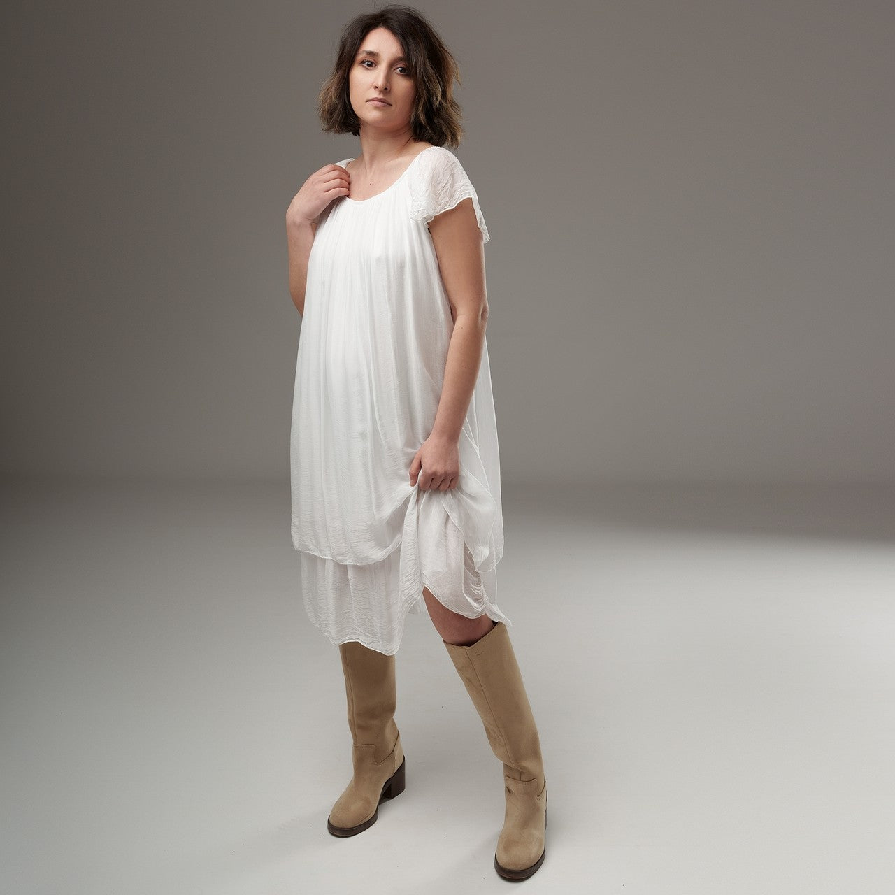 Rochie albă lejeră cu volane la umeri, din material semitransparent, purtată de model