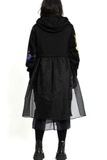 Spatele rochiei hanorac negre, cu glugă și cădere fluidă până sub genunchi.