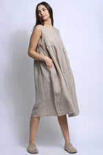 Rochie midi din in, fără mâneci, cu croială amplă și buzunare aplicate la piept, purtată frontal.