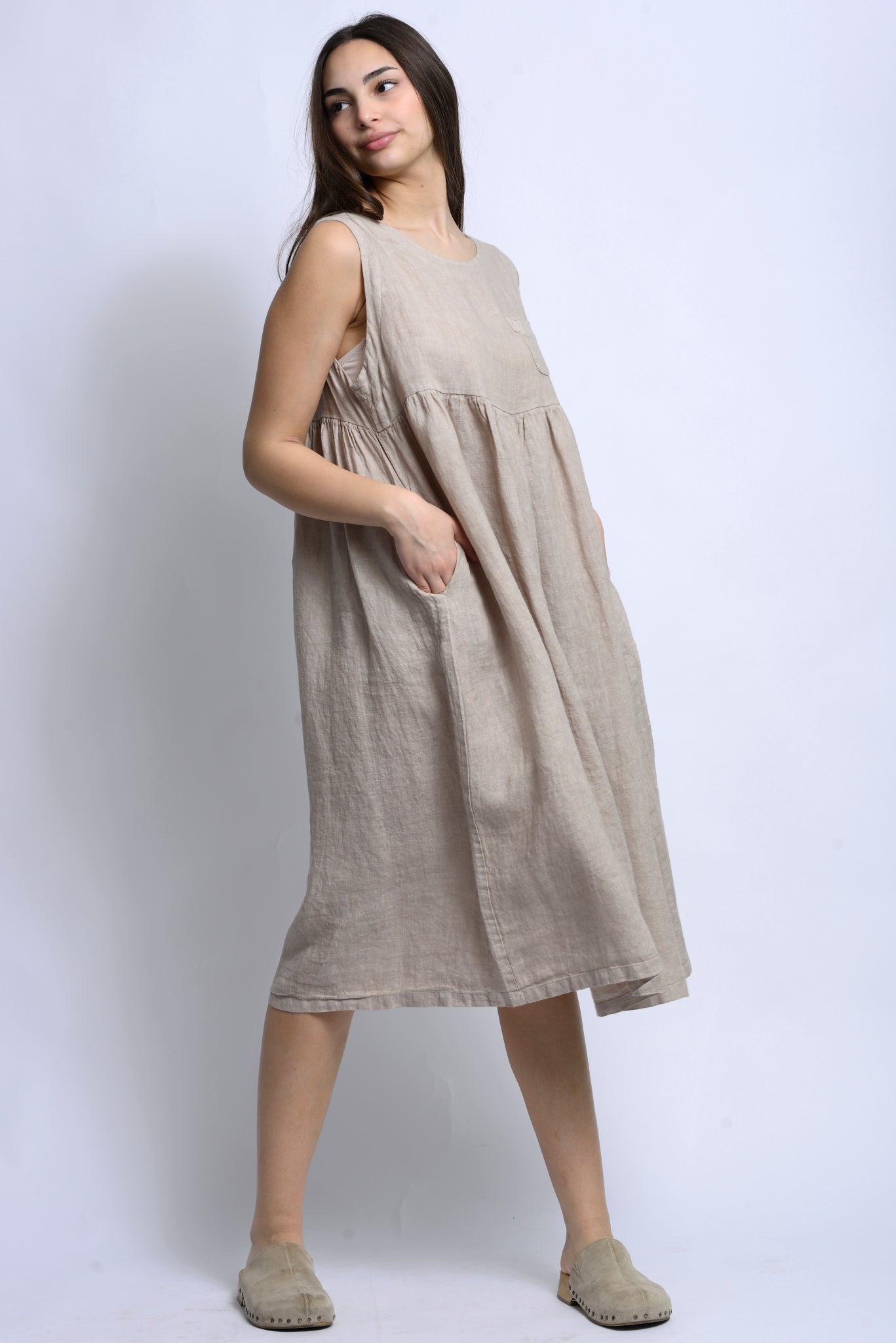 Rochie midi din in, fără mâneci, cu croială amplă și buzunare aplicate la piept, purtată frontal.