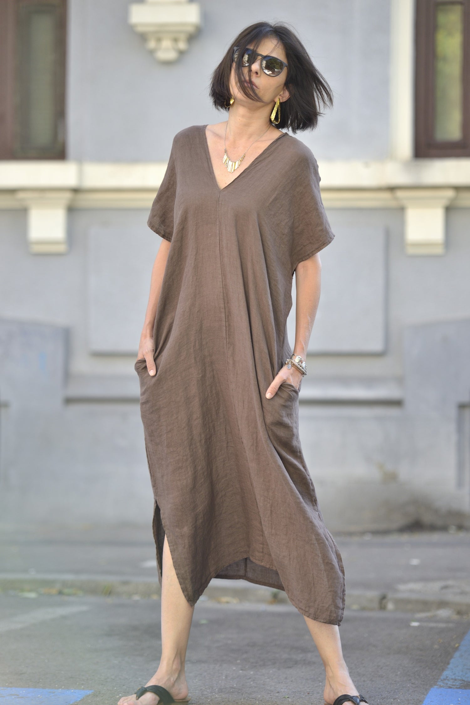 Rochie lejeră din in maro cu buzunare laterale și croială asimetrică, purtată casual.