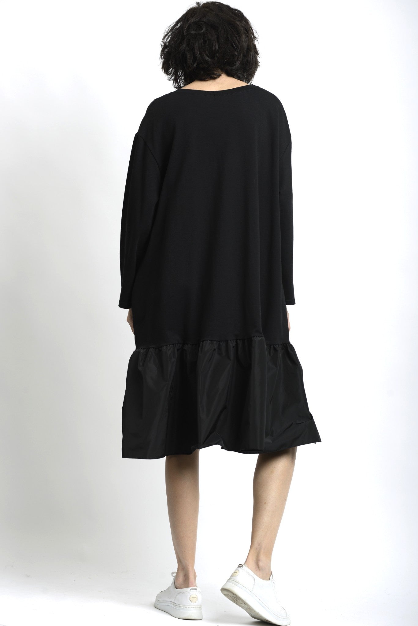 Spatele rochiei din jerse negru, cu linie simplă și volum amplu.