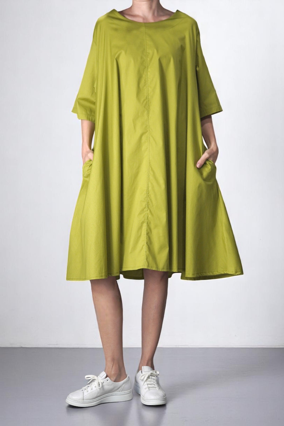 Rochie largă din bumbac într-o nuanță fresh de verde lime, cu mâneci trei sferturi și croi lejer tip A, purtată cu adidași albi. Buzunare laterale și design minimalist confortabil.