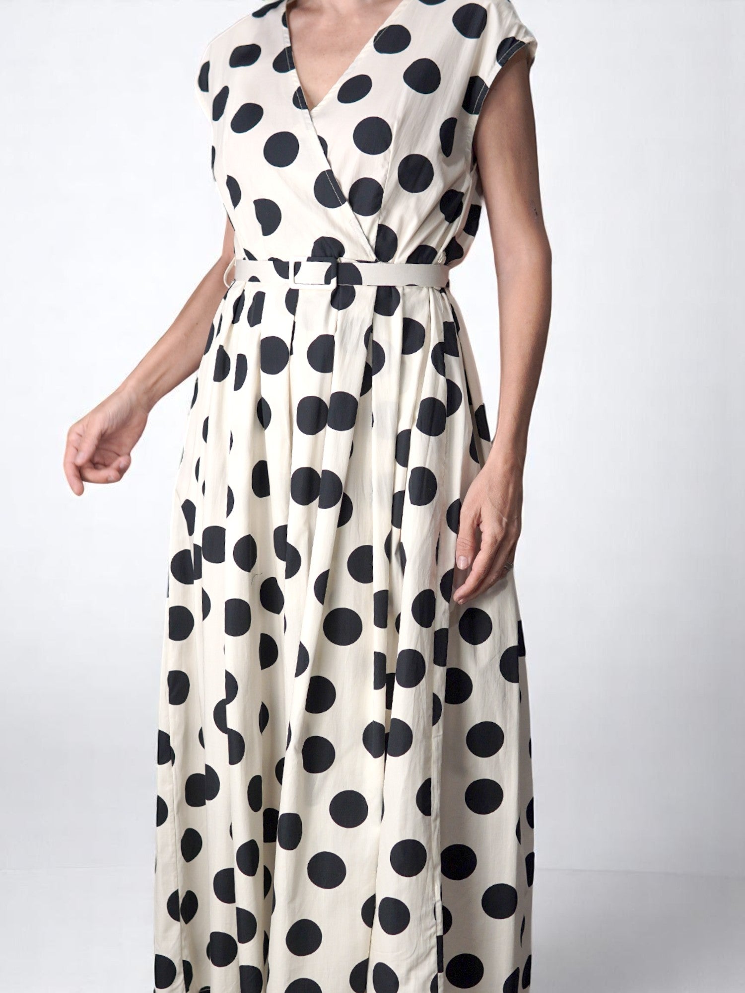 Rochie lungă albă cu buline negre, cu croială petrecută, curea în talie și lungime maxi. All Above Boutique.