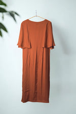 Rochie midi cărămizie cu mâneci fluture, văzută din spate, evidențiind croiala elegantă și fluiditatea materialului.