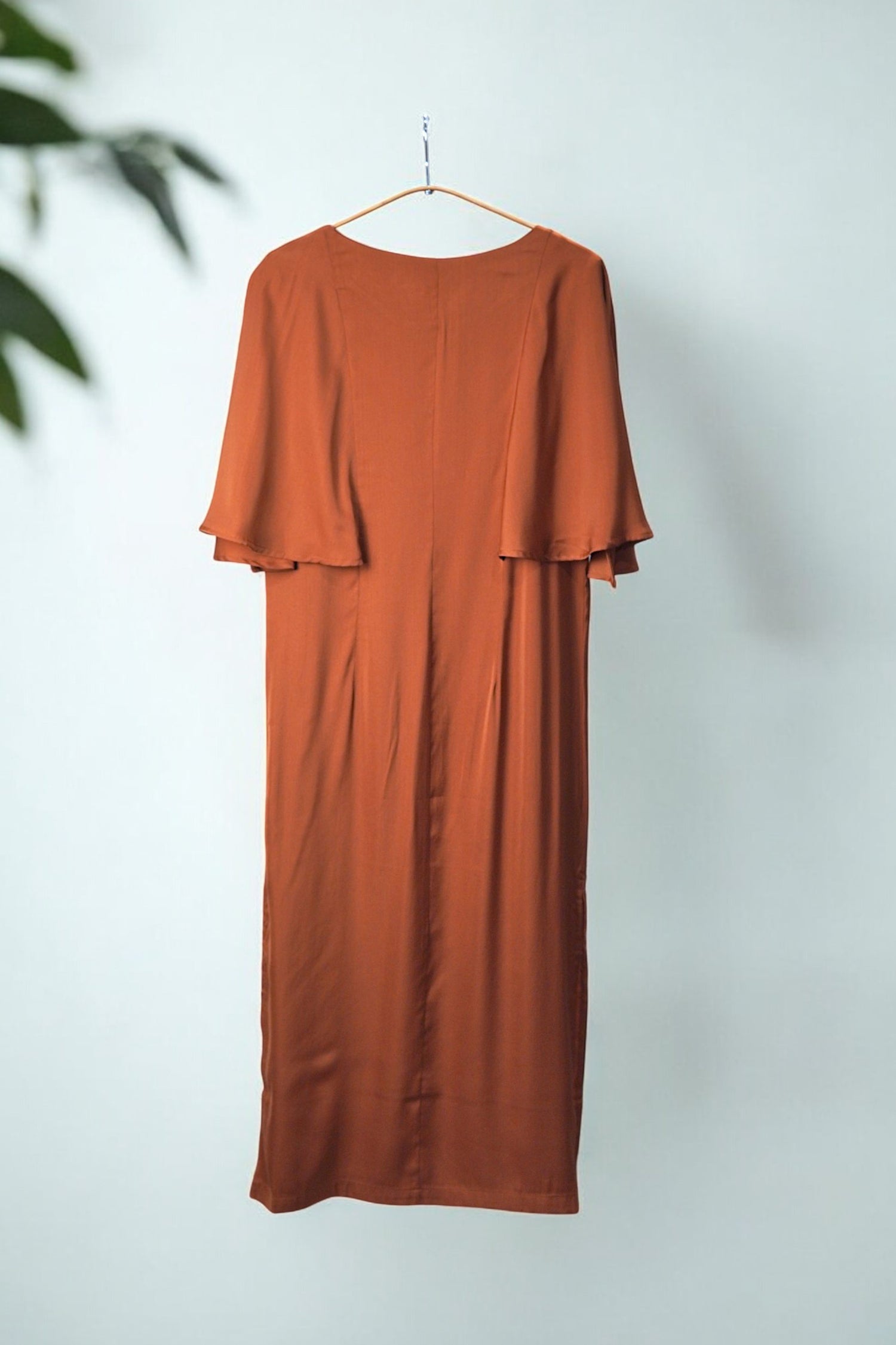 Rochie midi cărămizie cu mâneci fluture, văzută din spate, evidențiind croiala elegantă și fluiditatea materialului.