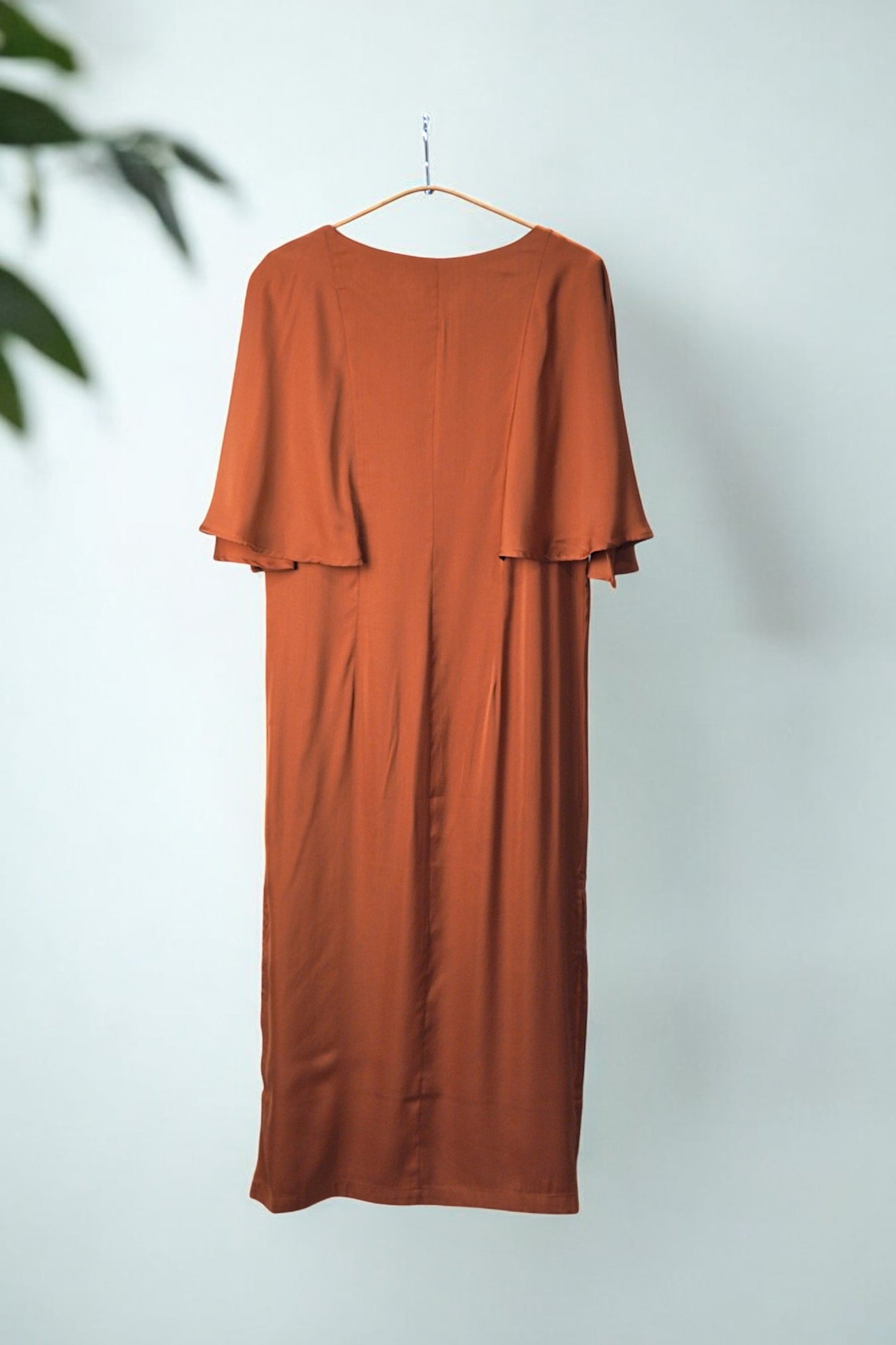 Rochie midi cărămizie cu mâneci fluture, văzută din spate, evidențiind croiala elegantă și fluiditatea materialului.